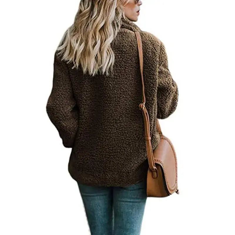 Woman wearing a cozy brown fur winter coat, paired with a brown shoulder bag and jeans, showcasing stylish winter fashion.